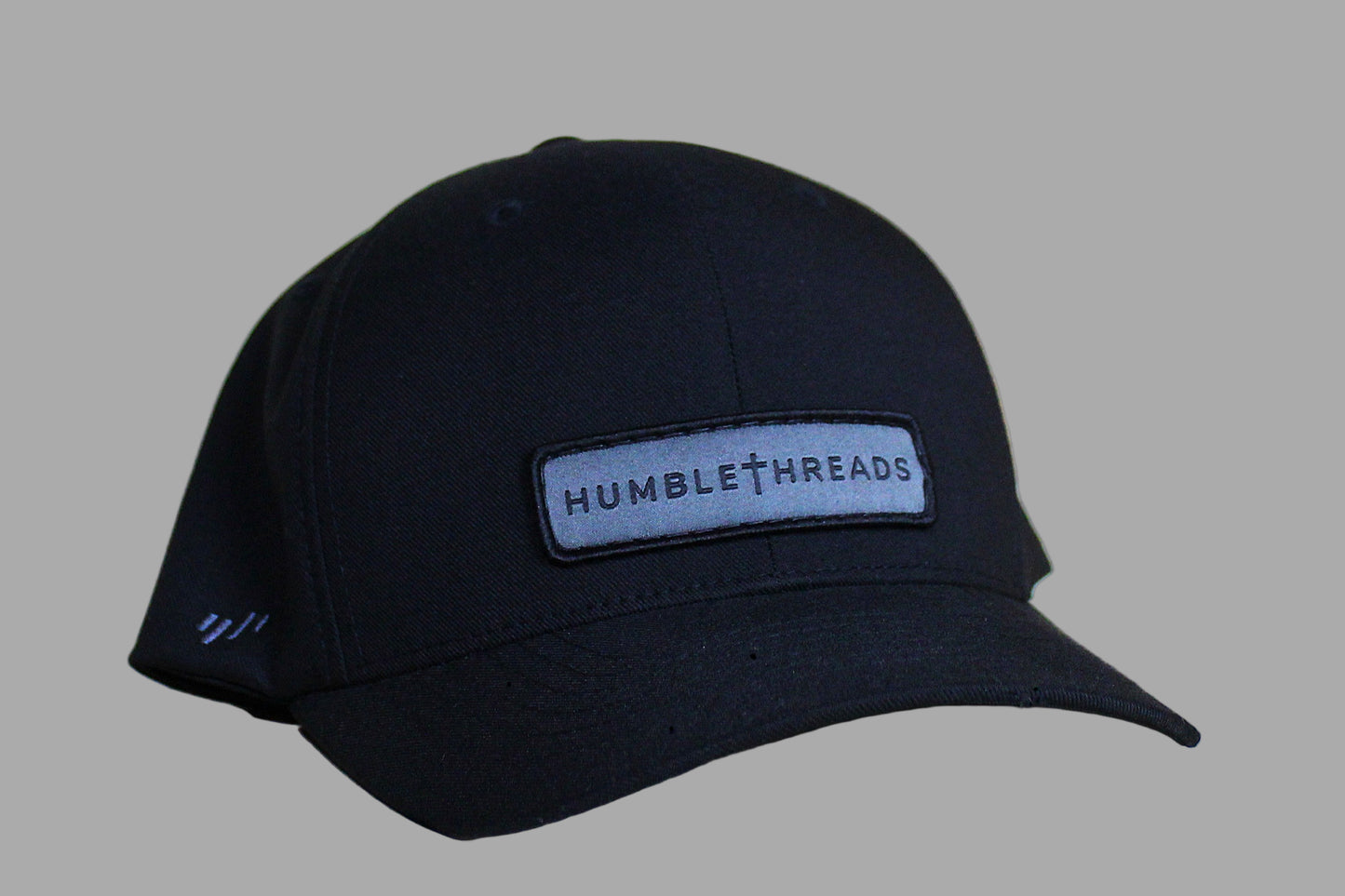 Black cap with 'Humble Threads' logo on a light wooden surface