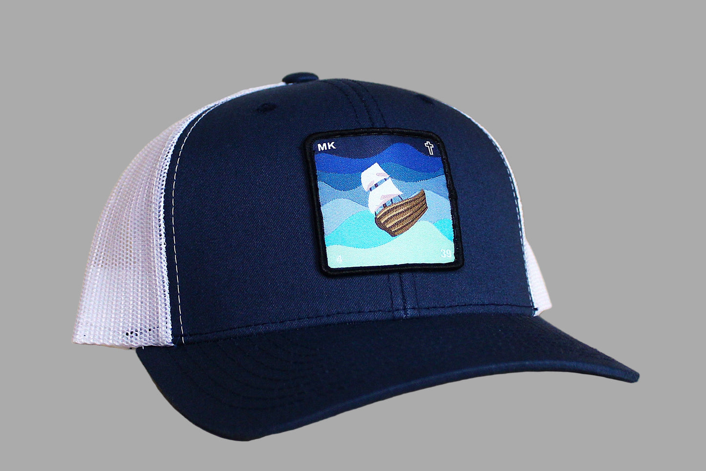 Navy blue cap with white mesh back and ship patch on a wooden surface