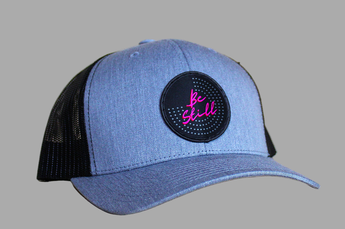 Blue and black cap with a pink and black patch on a wooden surface