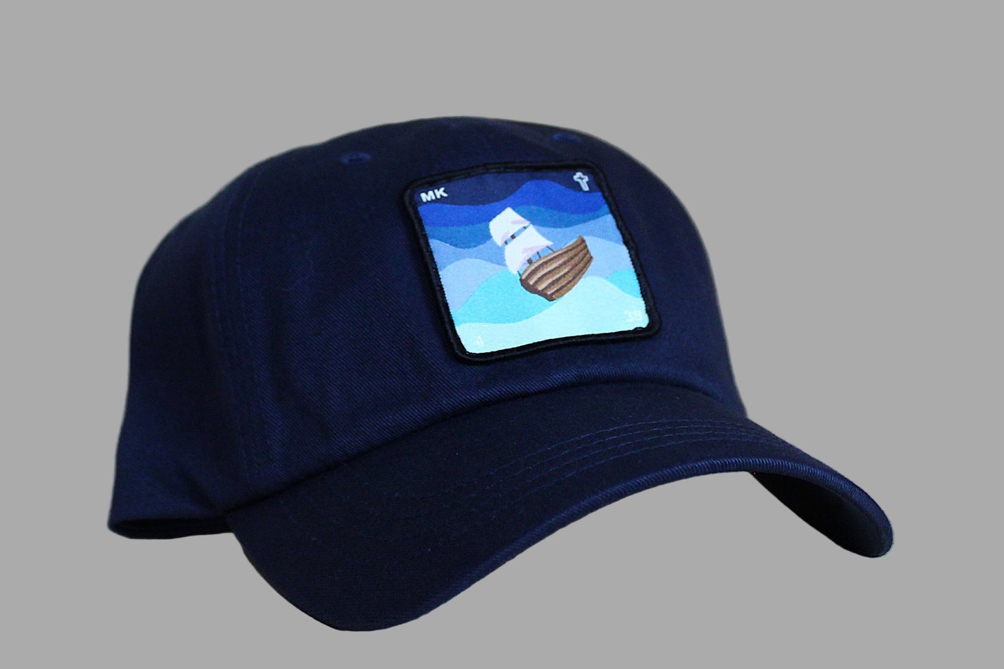Navy blue cap with a graphic of a ship on a light wood background