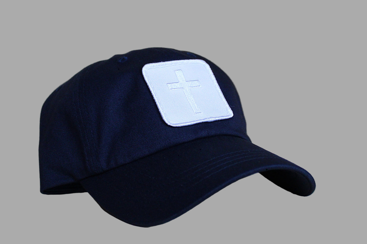 Navy blue cap with a white cross patch on a wooden surface