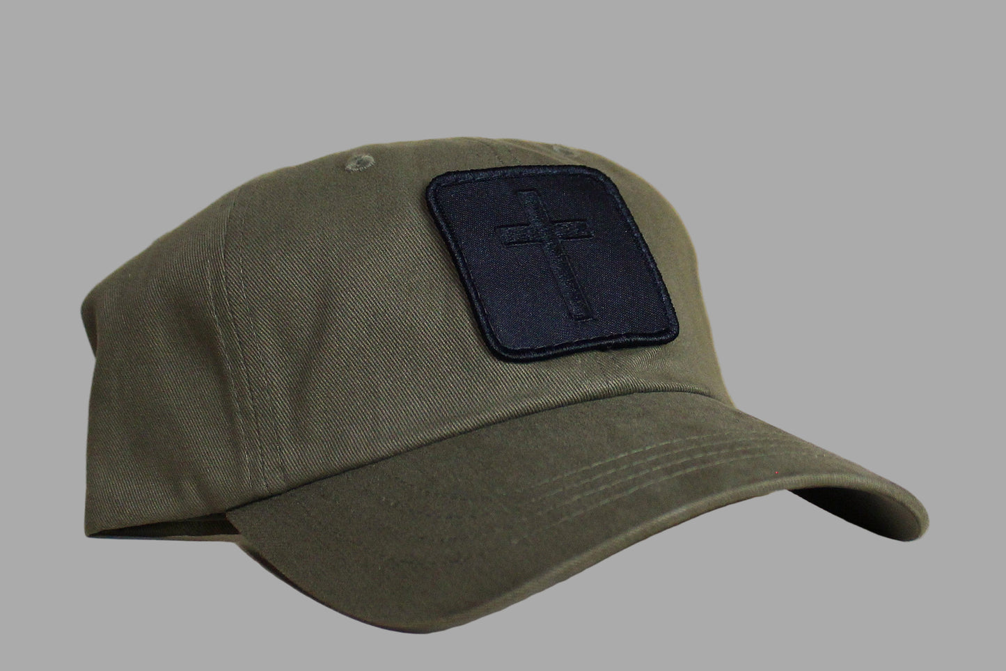 Green cap with a black patch featuring a cross on a light wooden background