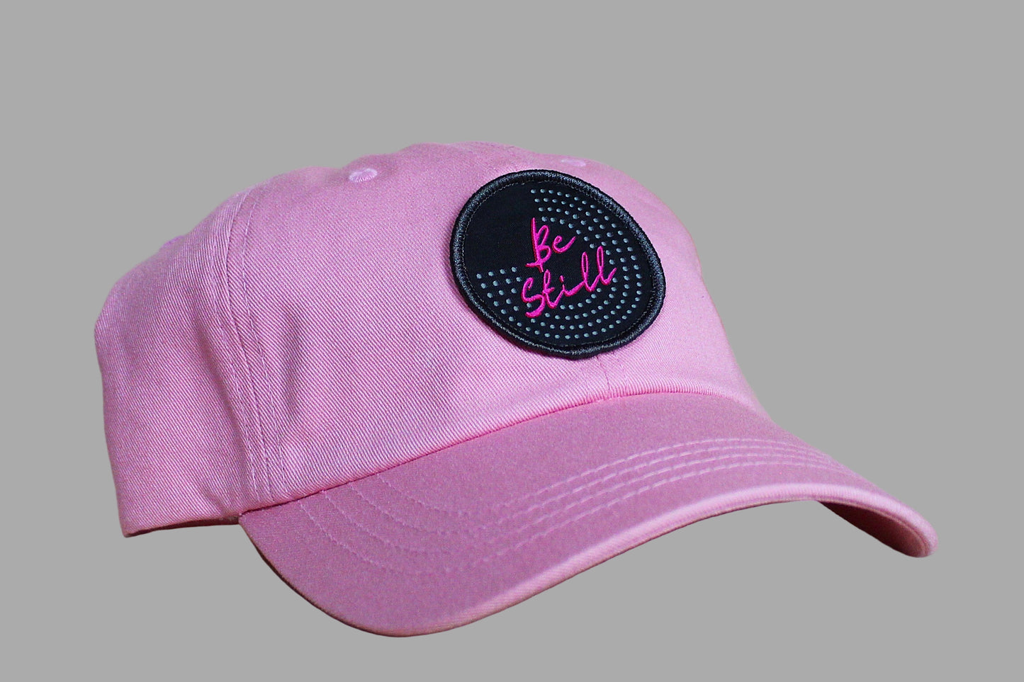 Pink cap with a black patch on a wooden surface
