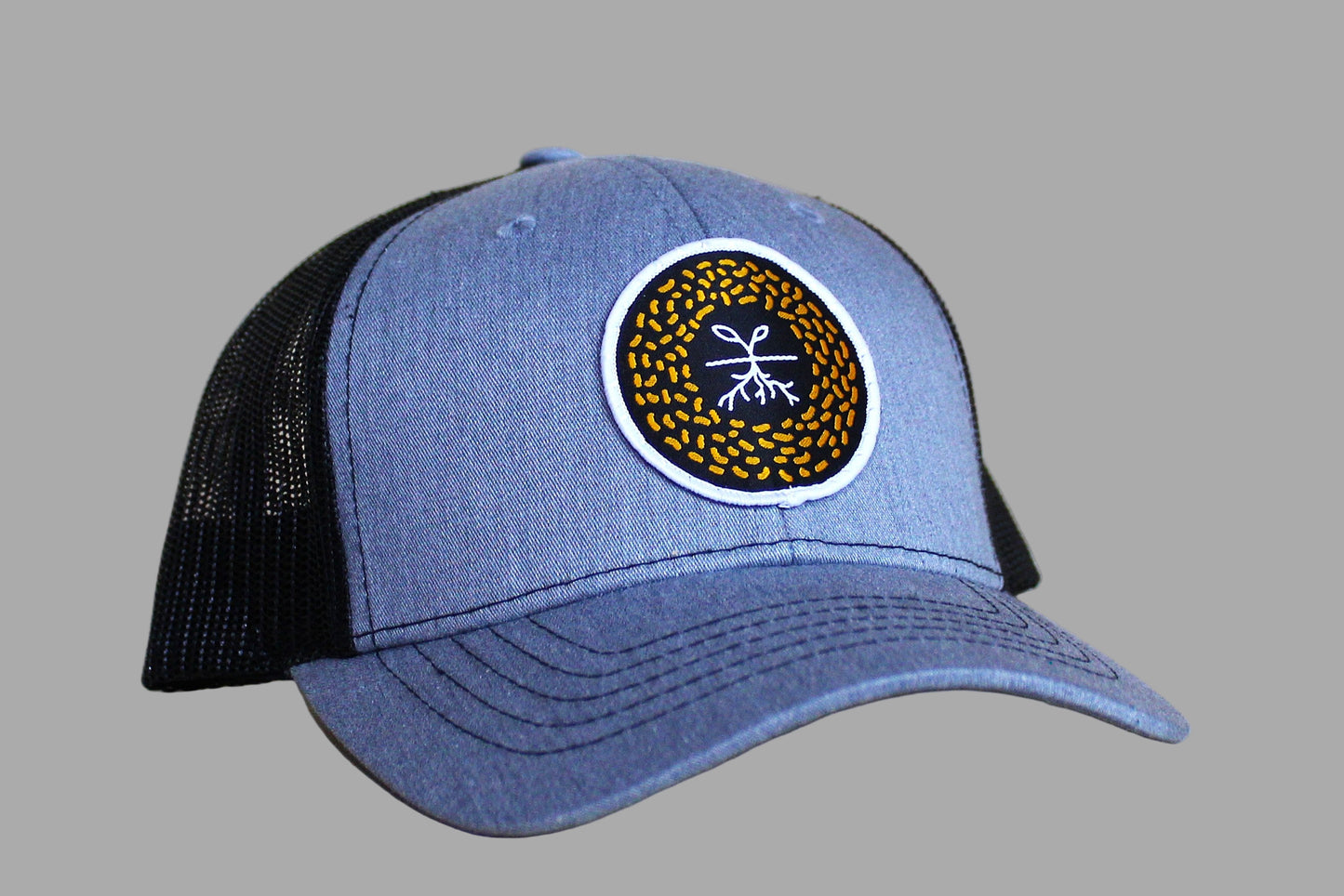 Blue trucker cap with black mesh back and circular logo on a light wooden surface
