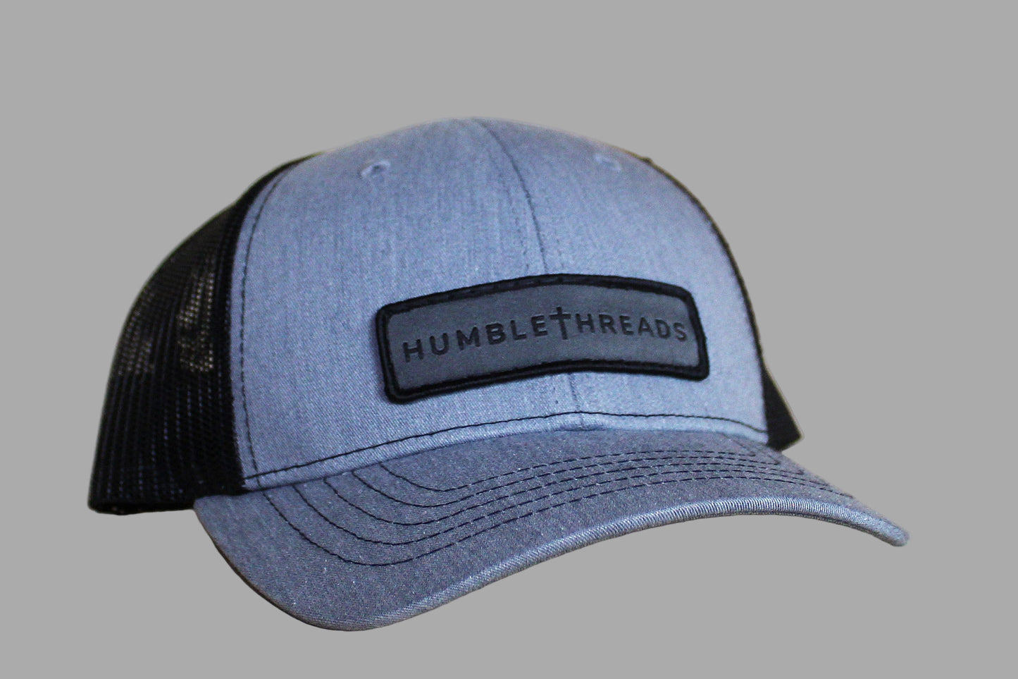 Blue and black cap with 'Humble Threads' logo on a light wooden surface
