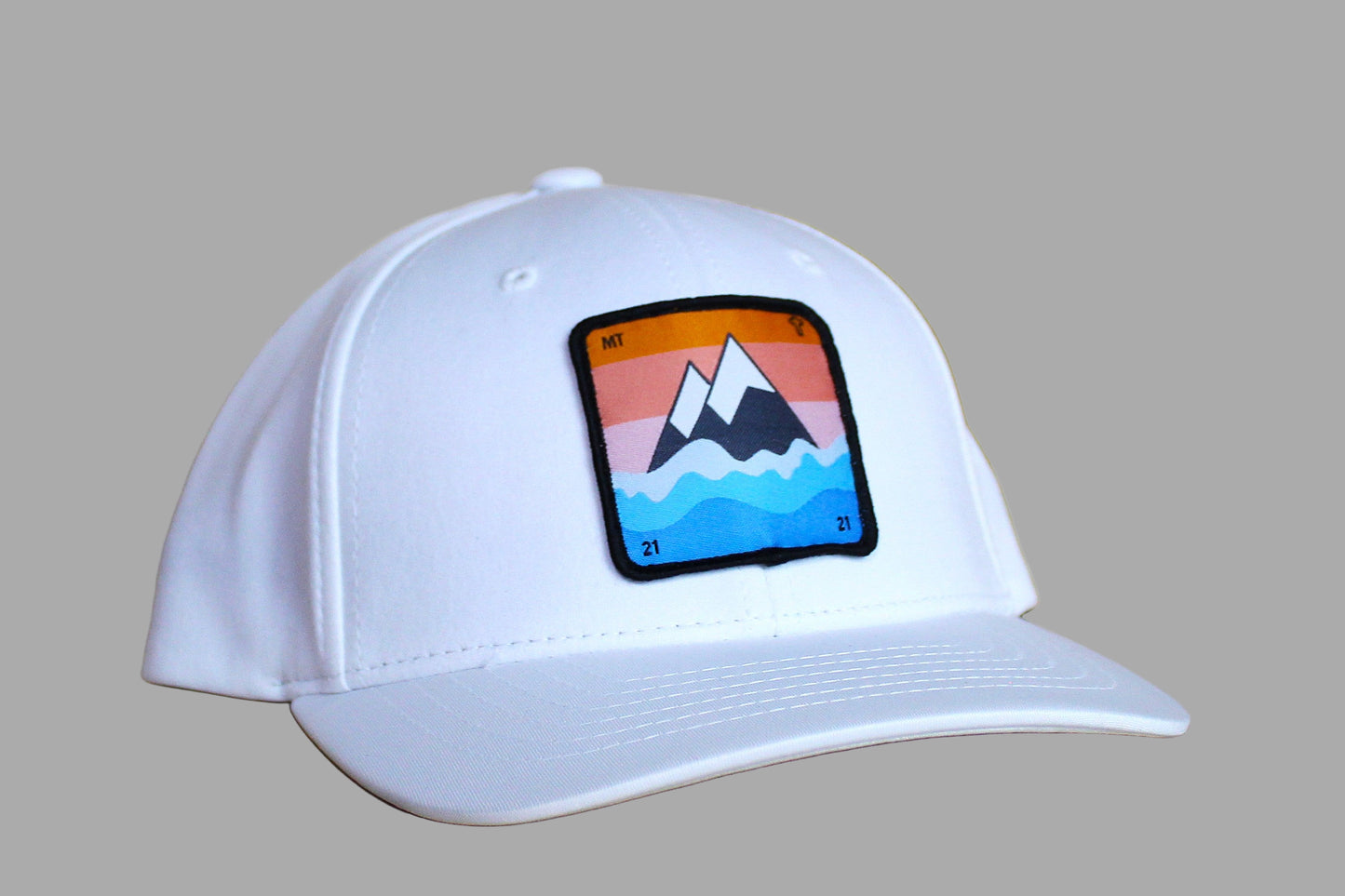White cap with a colorful mountain patch on a wooden surface
