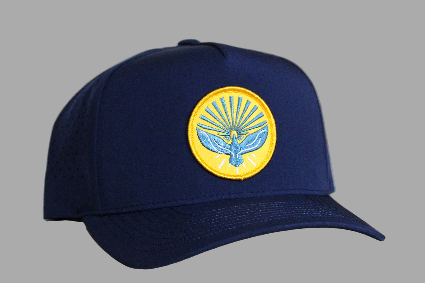 Navy blue cap with a yellow emblem featuring a bird design on a light wooden background