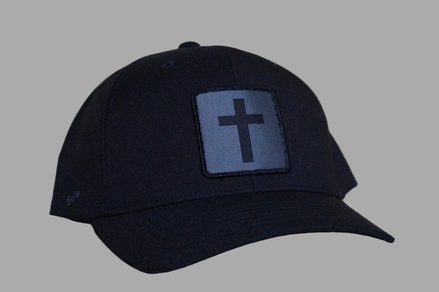 Black cap with a cross emblem on a light wooden surface