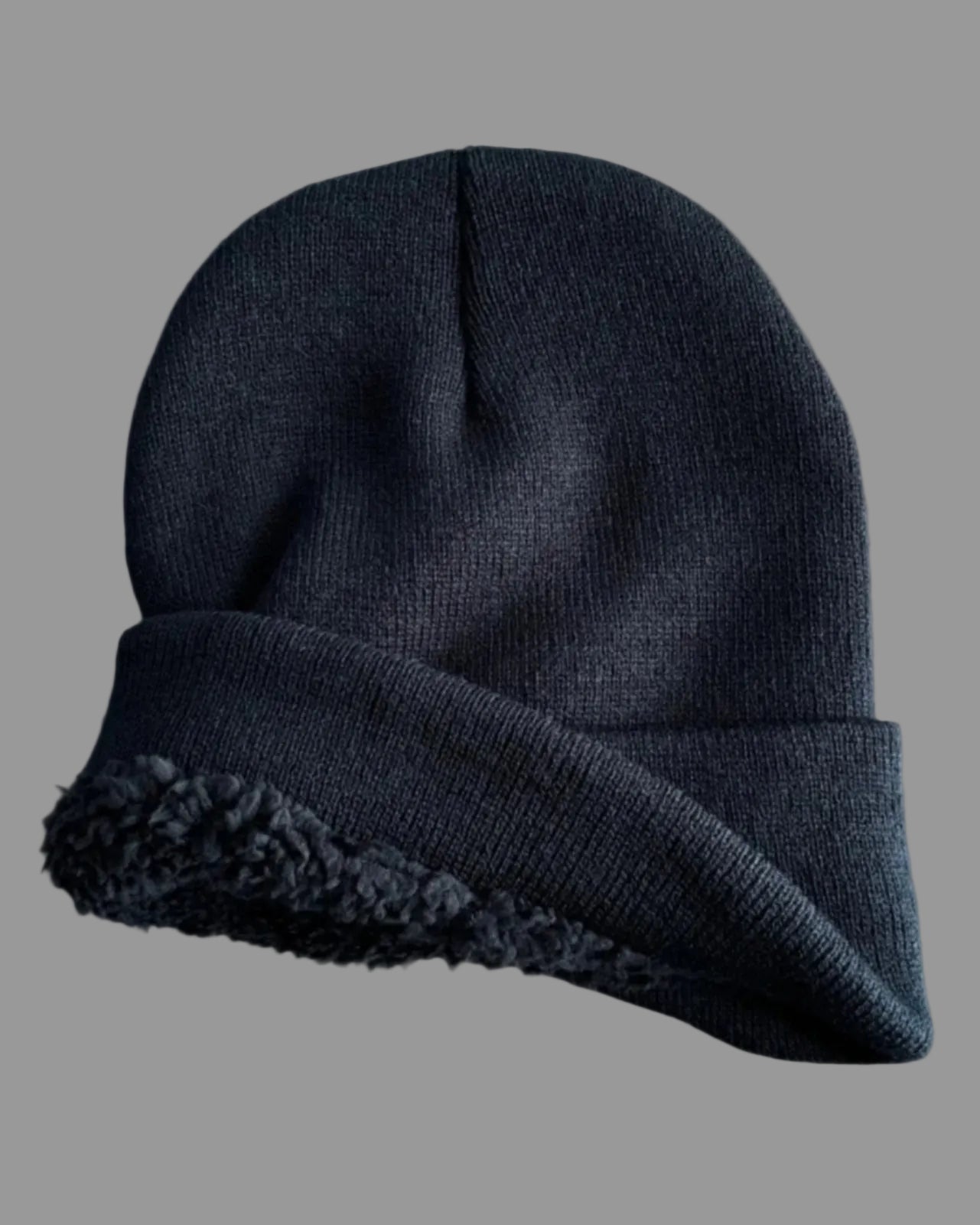 Dark gray knit beanie with fleece lining on a light gray background
