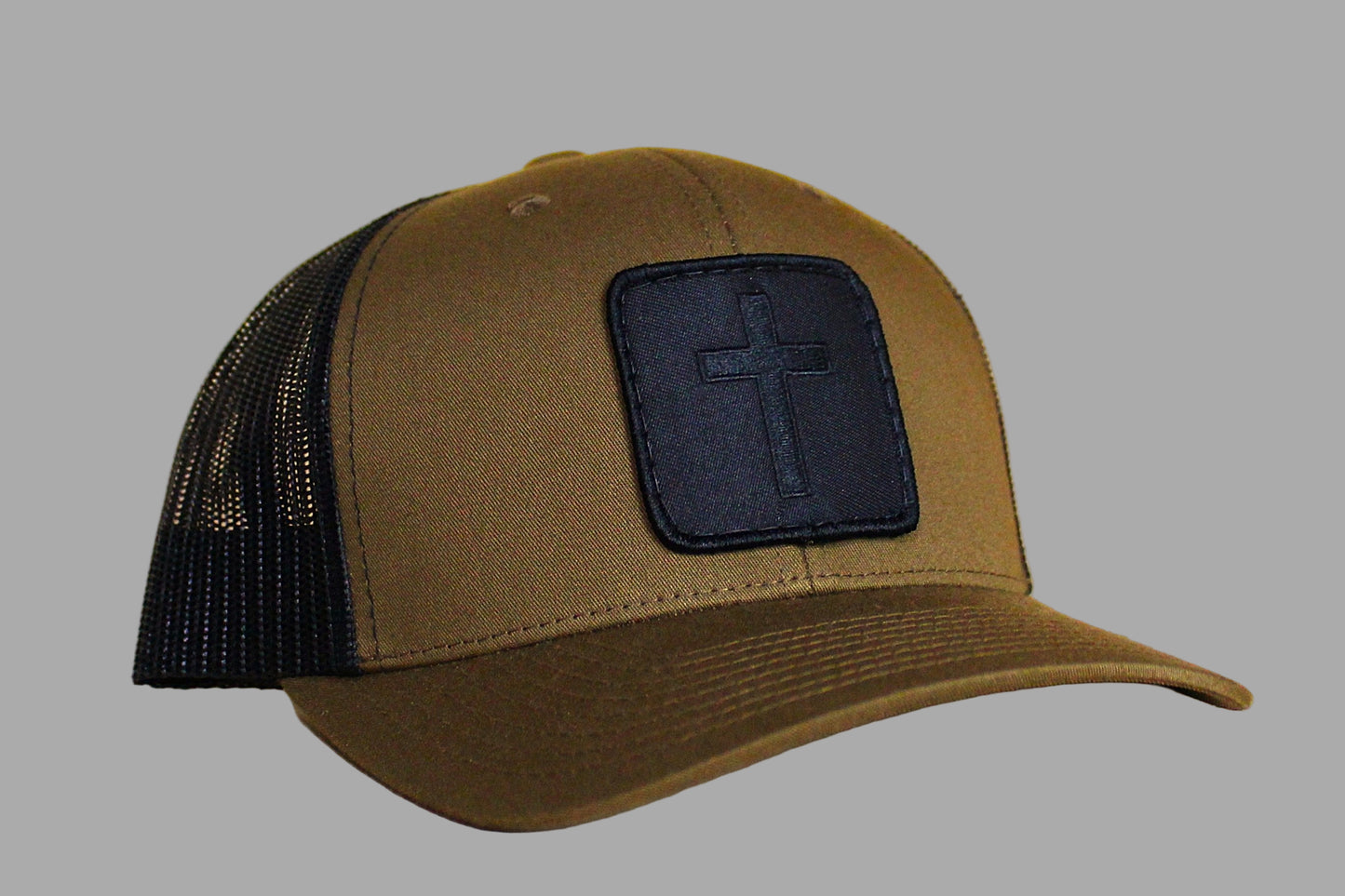 Brown cap with black mesh back and cross patch on a gray background