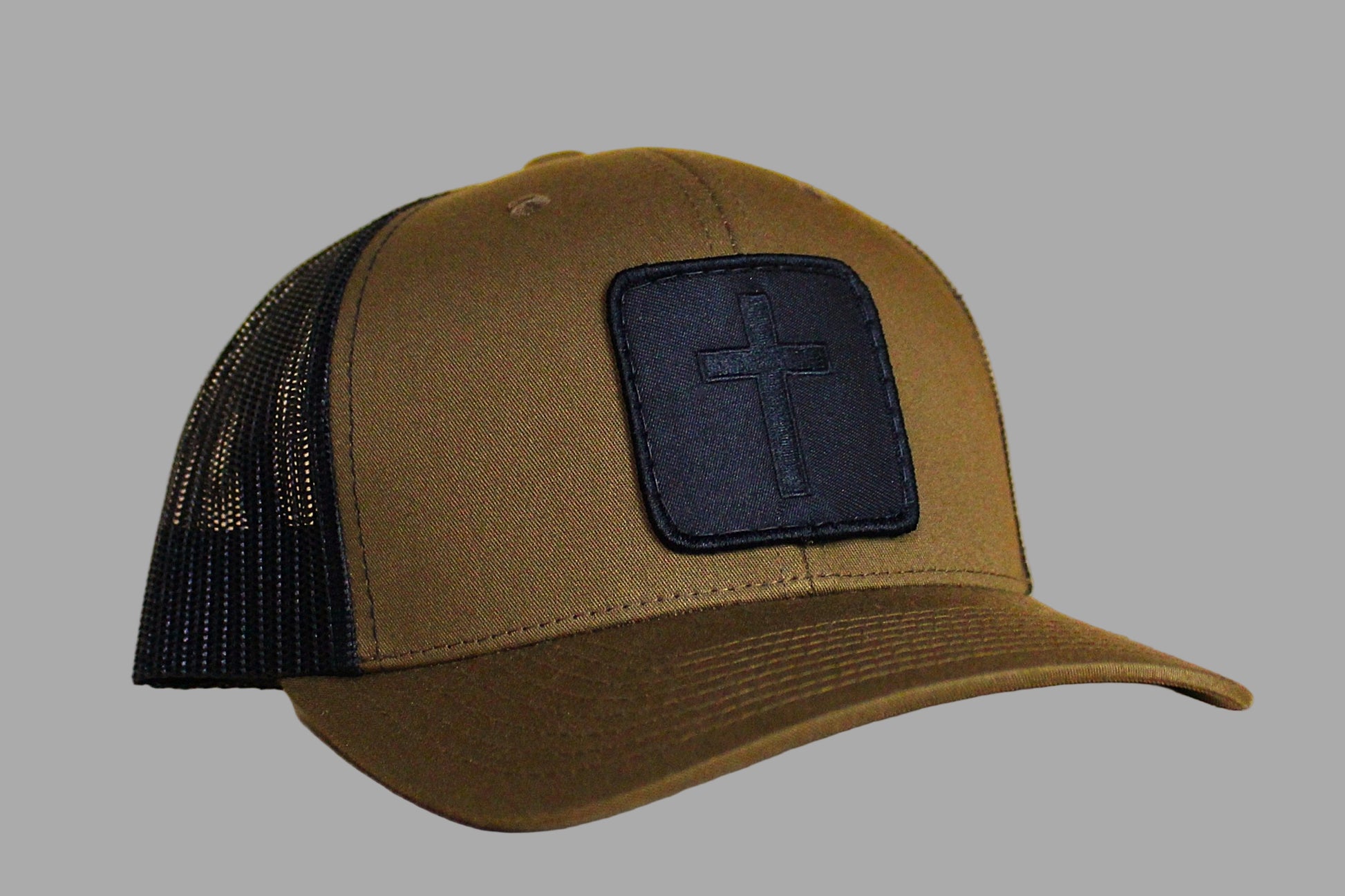 Brown cap with black mesh back and cross patch on a gray background