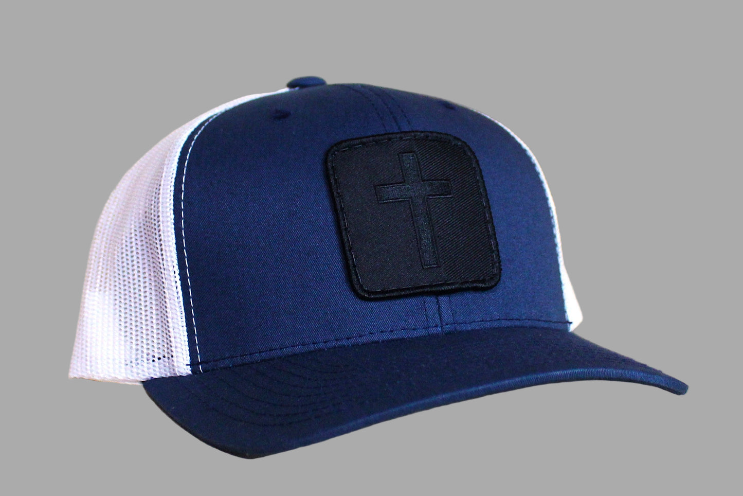 Blue and white cap with a black patch featuring a cross on a wooden surface
