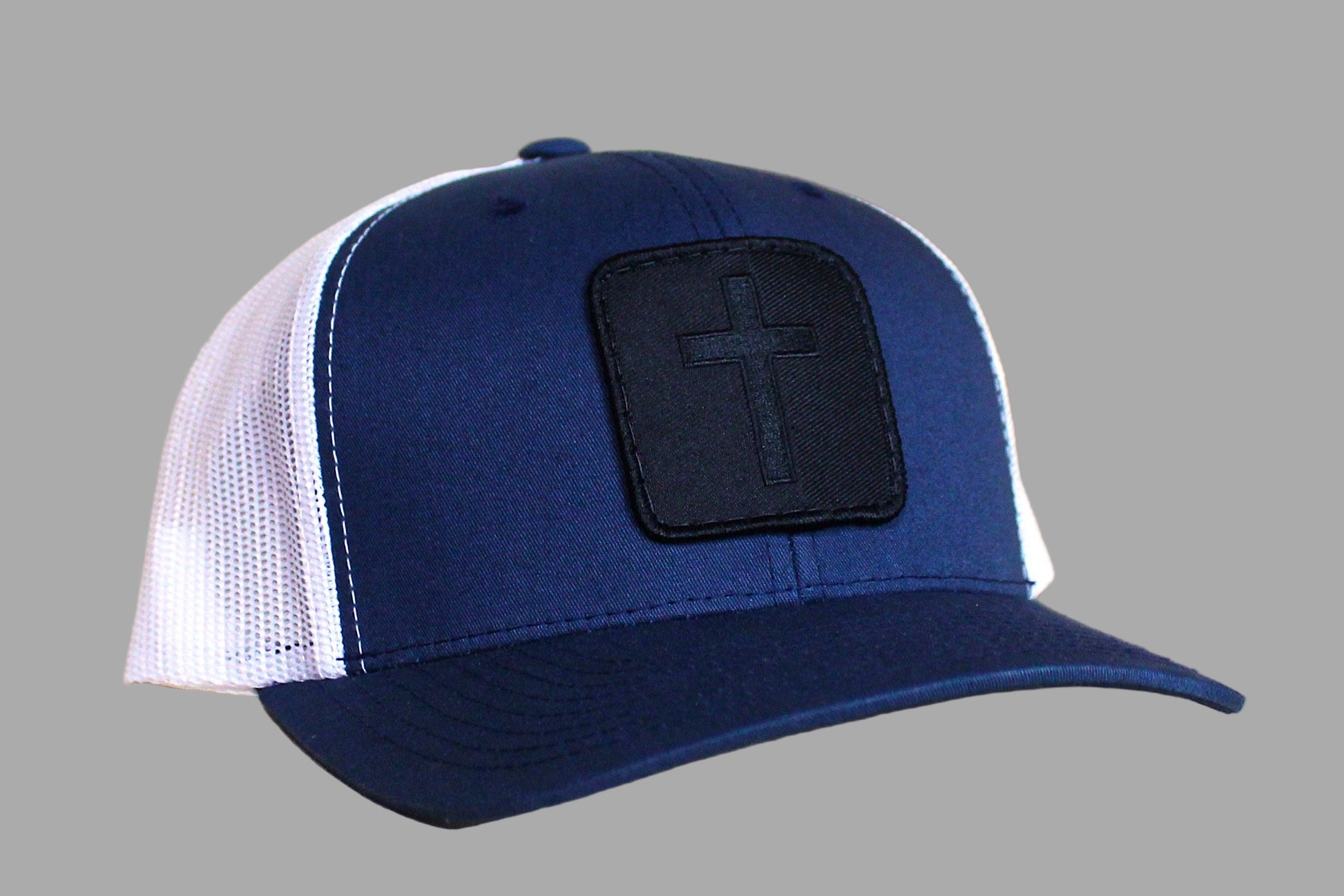 Blue and white cap with a black patch featuring a cross on a wooden surface