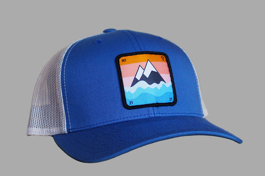 Blue trucker cap with a mountain patch on a wooden surface