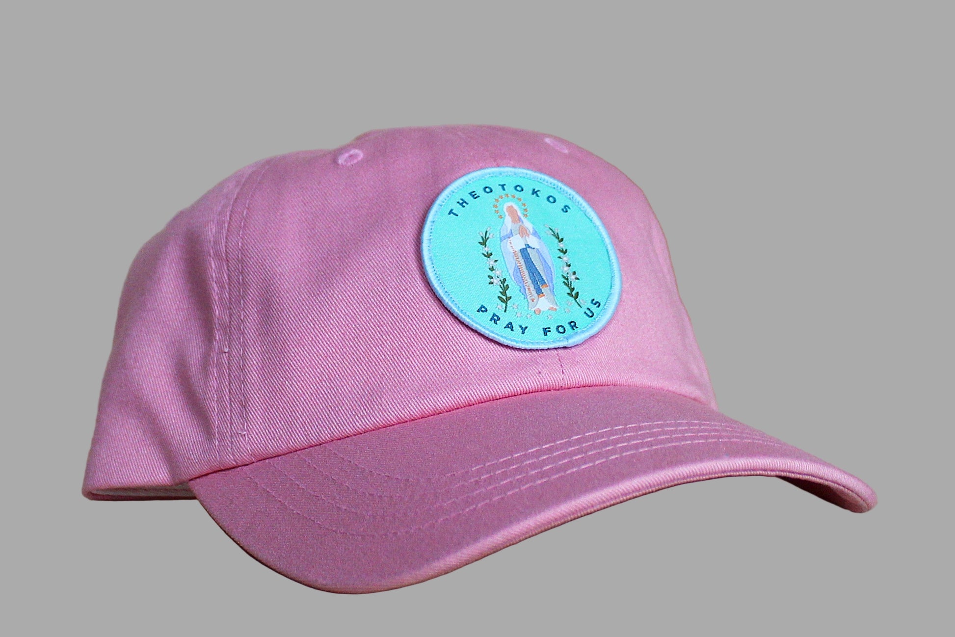Pink cap with a blue and green sticker on a wooden surface