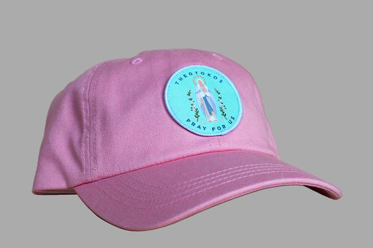 Pink cap with a blue and green sticker on a wooden surface