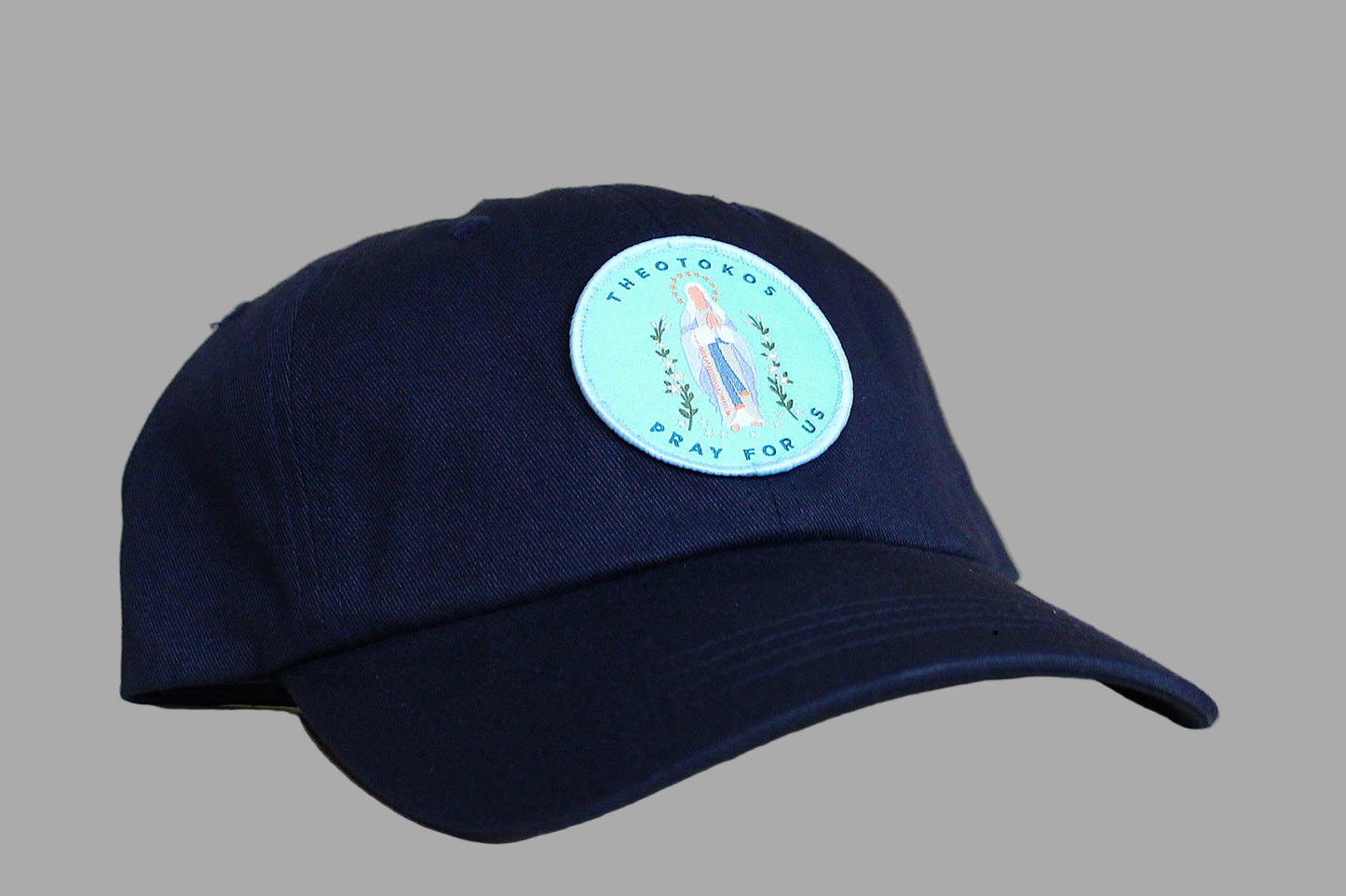 Navy blue cap with a circular patch featuring a religious icon on a wooden surface.