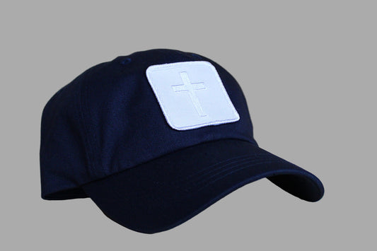 Navy blue cap with a white cross patch on a wooden surface