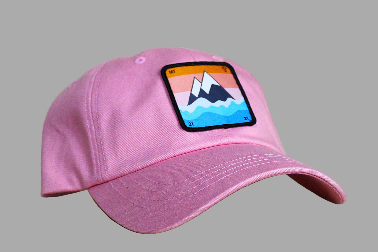 Pink baseball cap with a mountain patch on a wooden surface