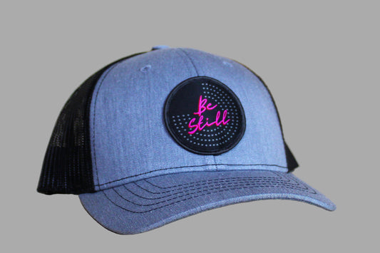 Blue and black cap with a pink and black patch on a light wooden surface