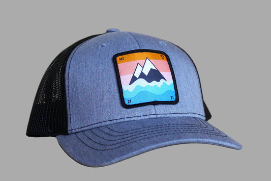 Blue trucker hat with a mountain and water patch on a wooden surface
