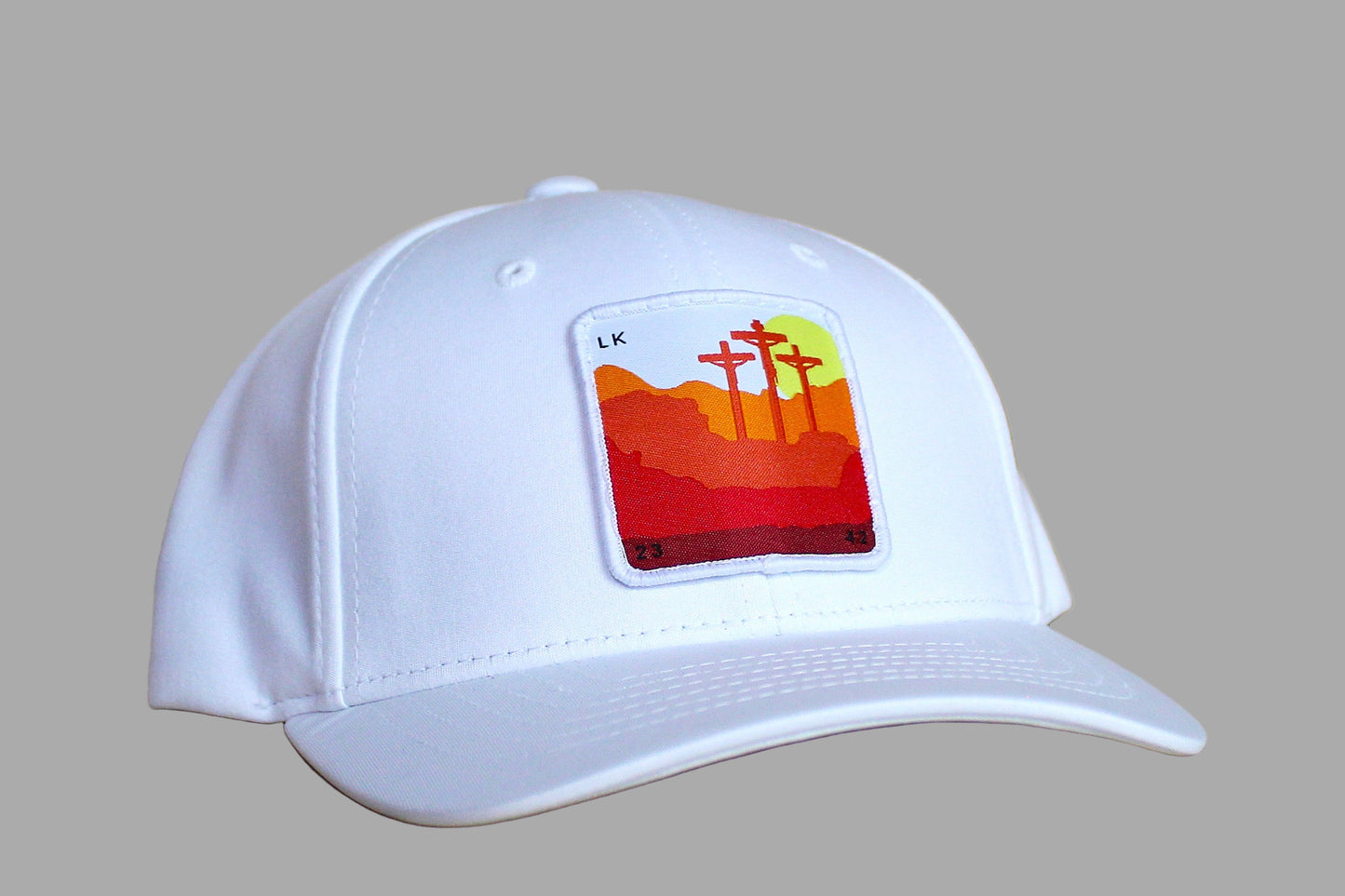 White cap with a colorful patch featuring crosses on a wooden surface