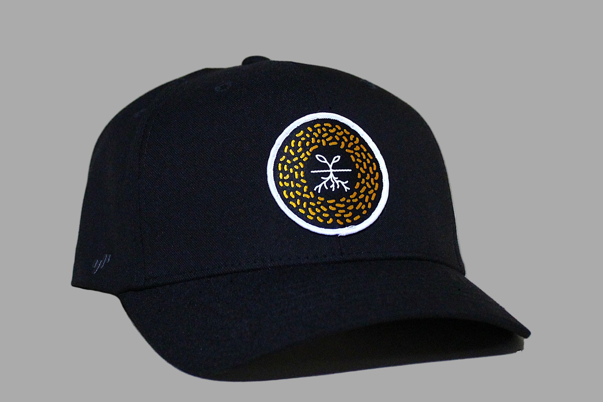 Black cap with a circular logo on a light wood background