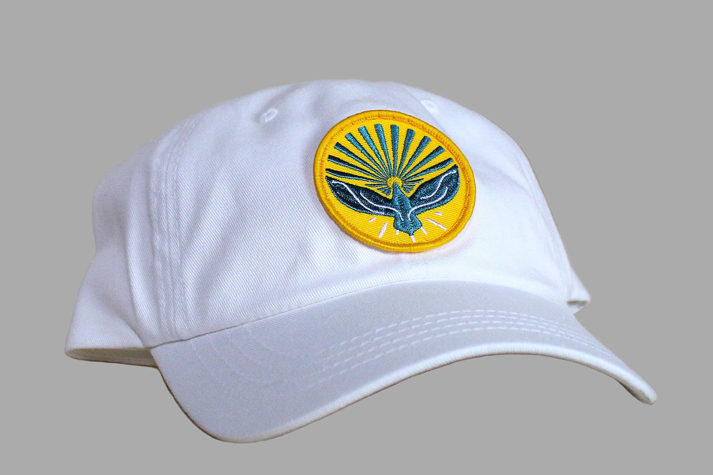 White cap with a yellow and blue emblem on a wooden surface