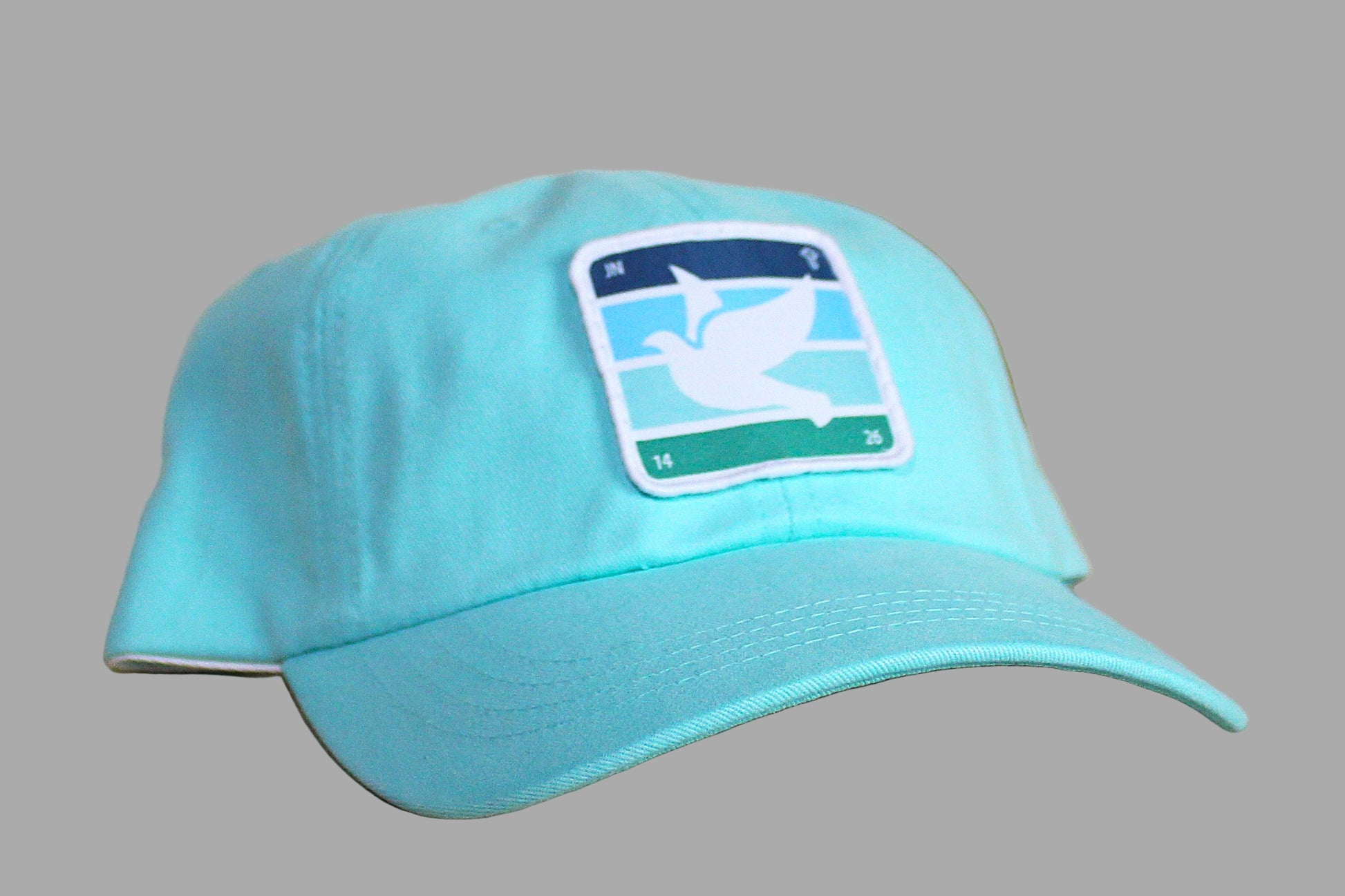 Turquoise cap with a logo on a wooden surface