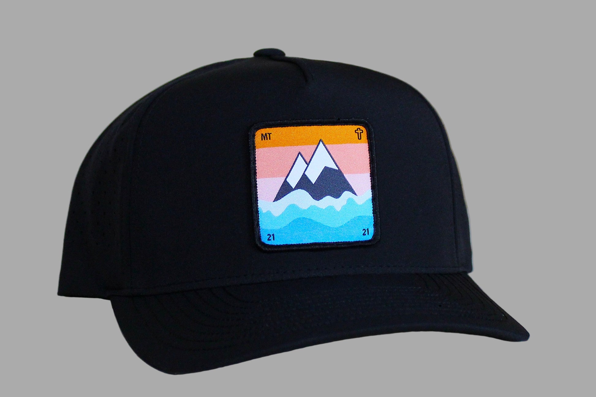 Black cap with a colorful mountain patch on a light wooden surface