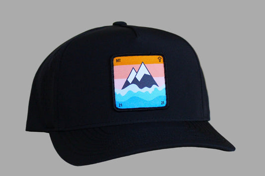 Black cap with a colorful mountain patch on a light wooden surface