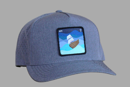 Gray cap with a patch featuring a ship on a wooden surface