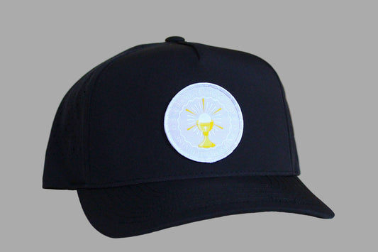 Black cap with a white emblem featuring a yellow design on a light wooden surface.