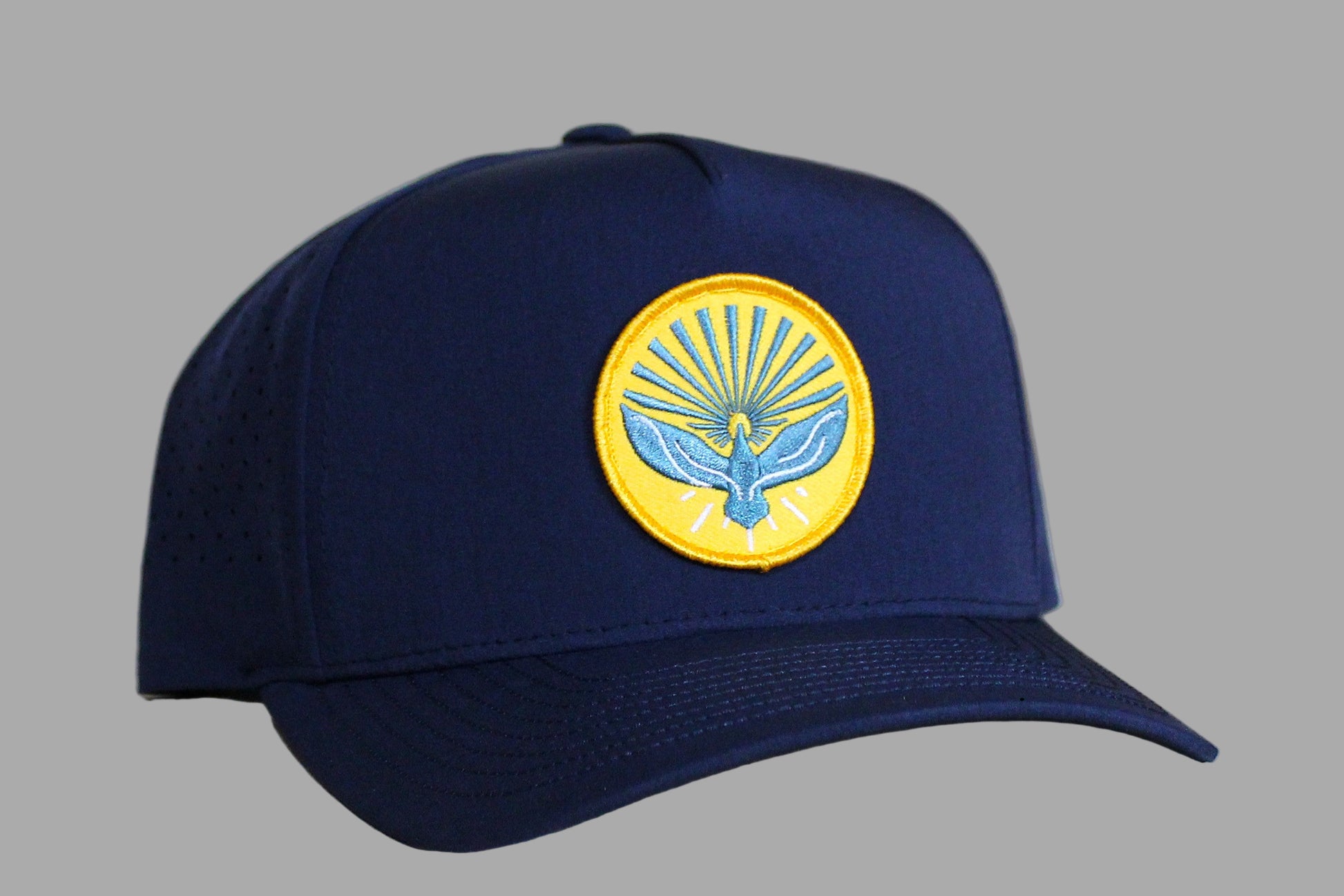 Navy blue cap with a yellow emblem featuring a bird design on a light wooden background
