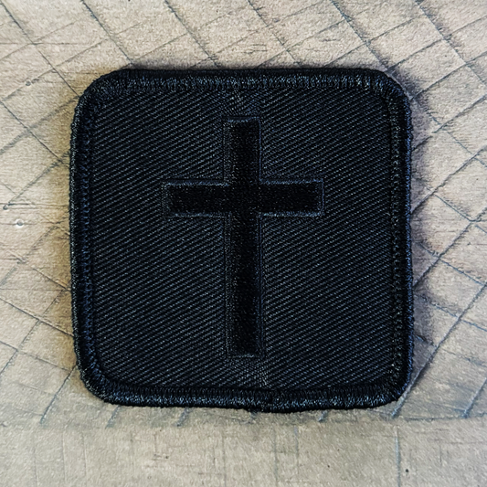 Black embroidered cross on a black twill background 